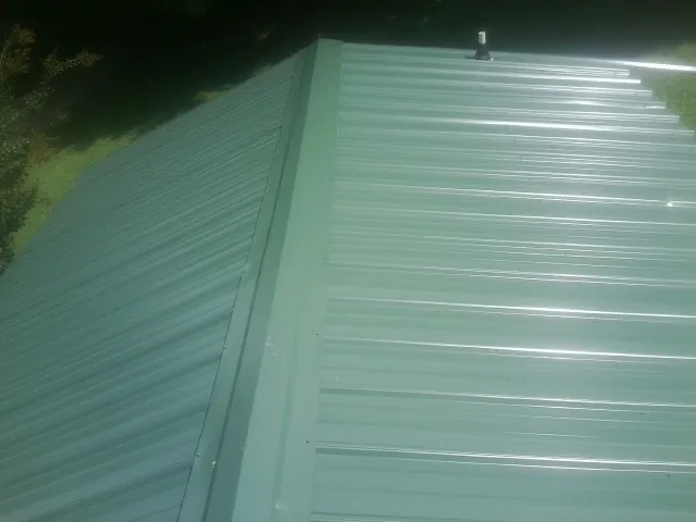 New green metal panels meeting at the ridge of a roof — Flat Roof Repair work by our crew in Southington