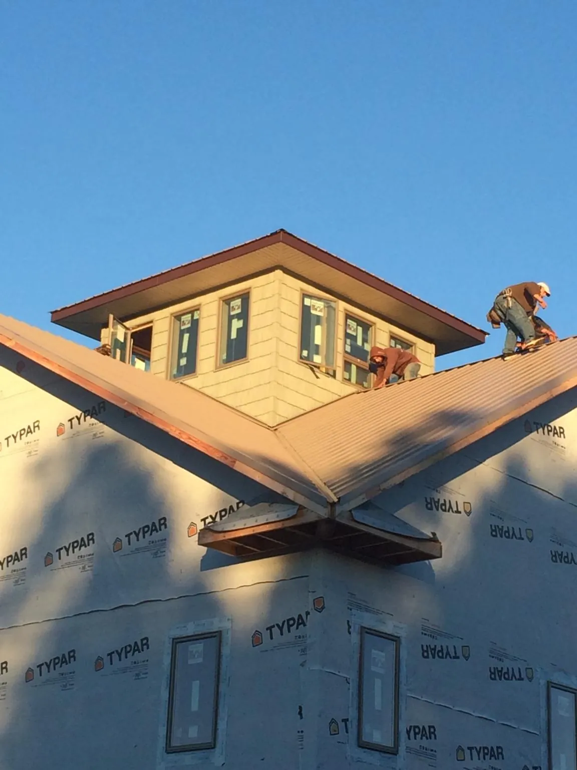 Roofers working around a rooftop cupola on a new metal roof at sunset — Roof Waterproofing in Southington by Roofing Brothers